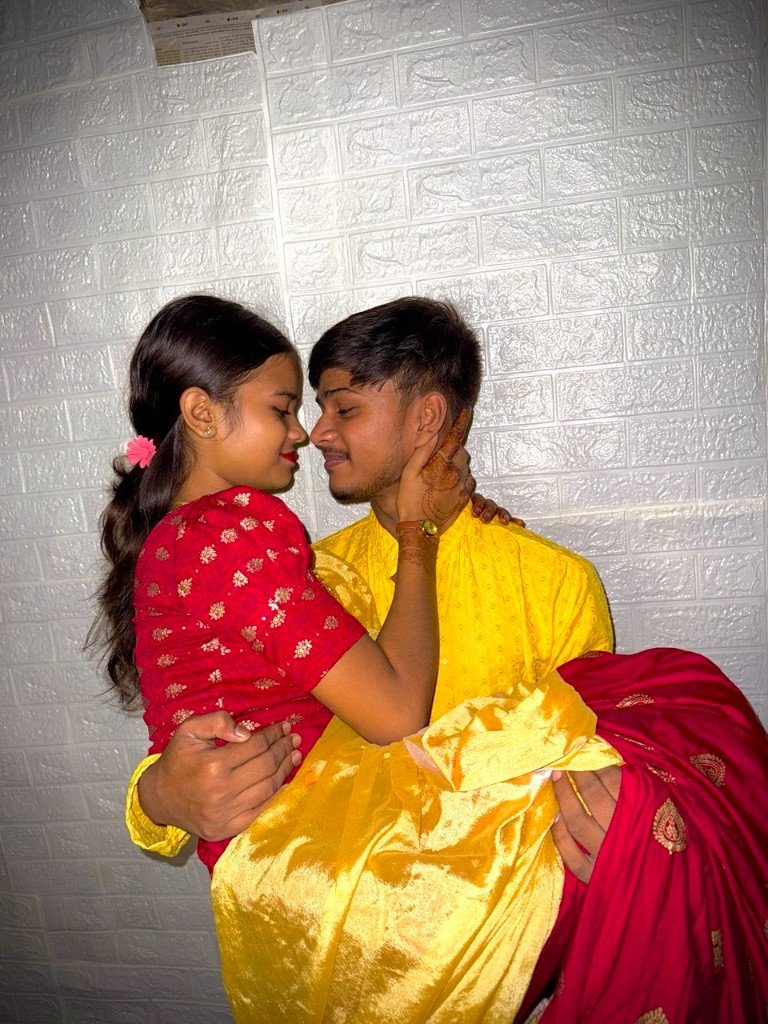 ओम गुड़िया को गोद में लिए हुए, लाल और पीले कपड़ों में